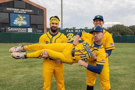 Banana Ball players in yellow uniforms posing on a baseball field