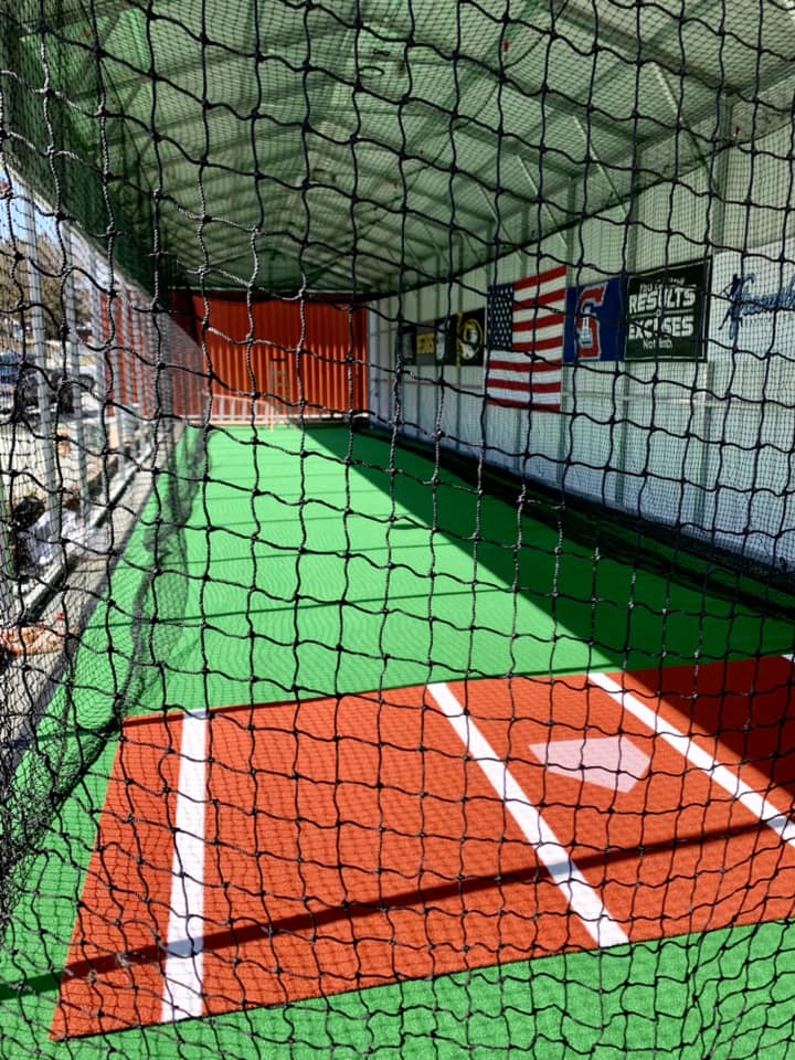 Team practicing in a batting cage facility